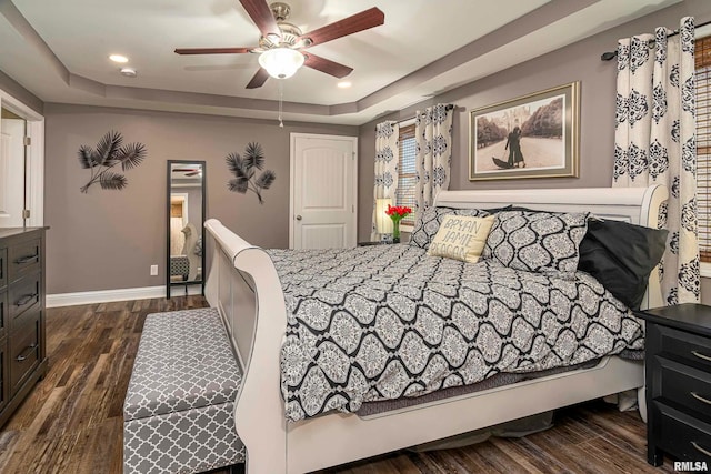 bedroom featuring dark hardwood / wood-style flooring, a raised ceiling, and ceiling fan