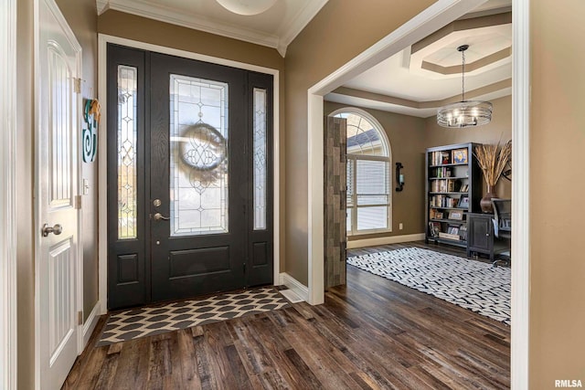 entrance foyer featuring dark hardwood / wood-style floors, crown molding, a tray ceiling, and a chandelier