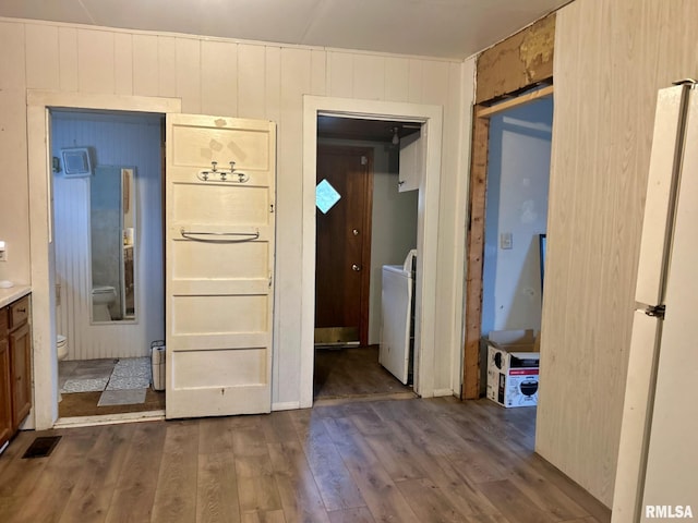 corridor featuring wood walls, dark hardwood / wood-style flooring, and washer / dryer