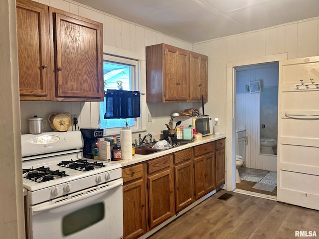 kitchen featuring white appliances, sink, wooden walls, and dark wood-type flooring