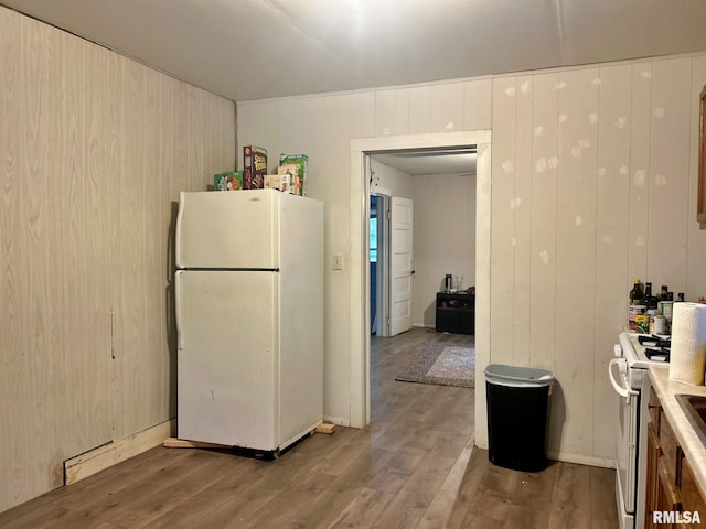 kitchen with hardwood / wood-style floors, white appliances, and wood walls