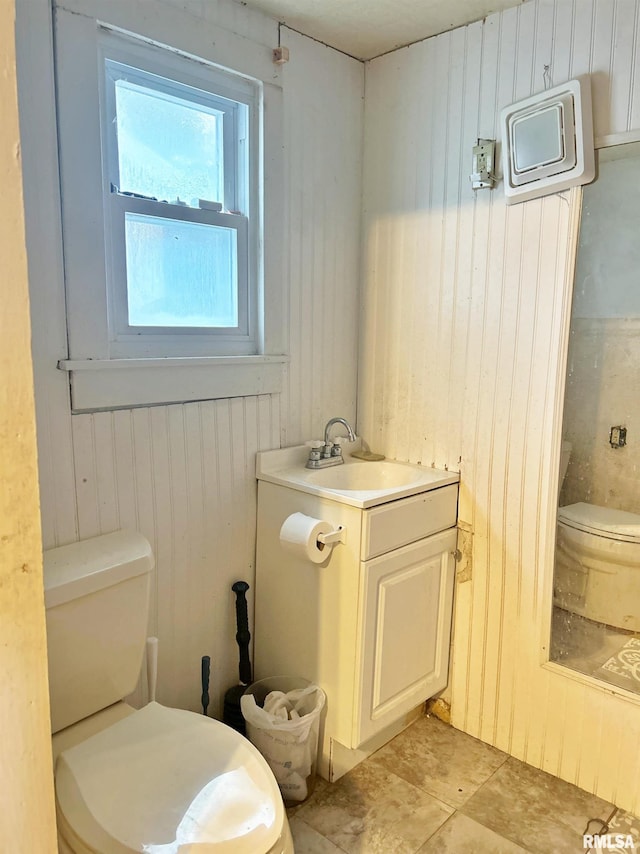 bathroom with wood walls, vanity, and toilet