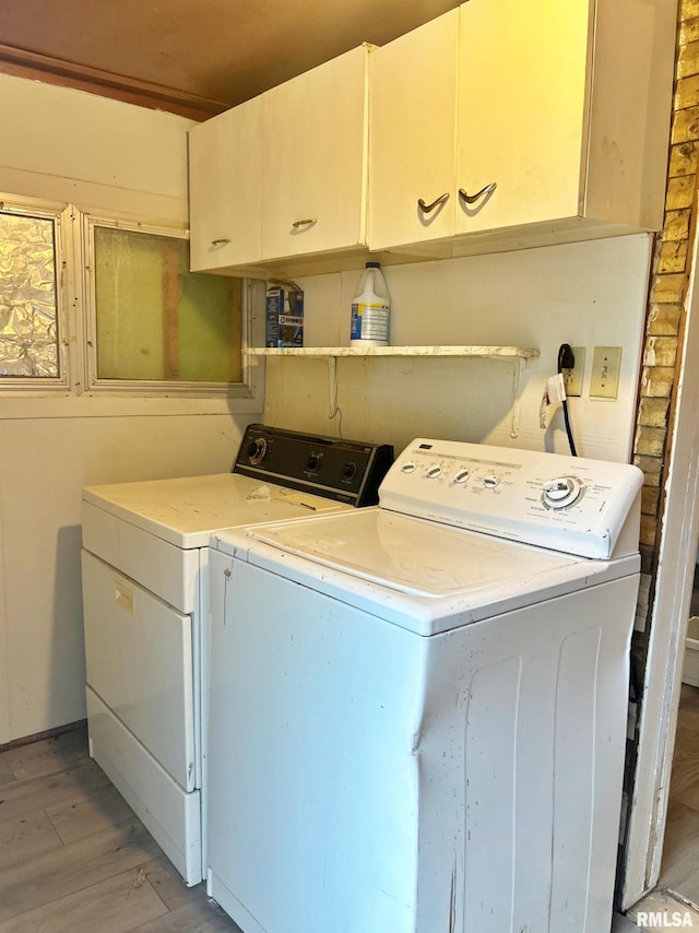 washroom with cabinets, light hardwood / wood-style flooring, and washer and clothes dryer