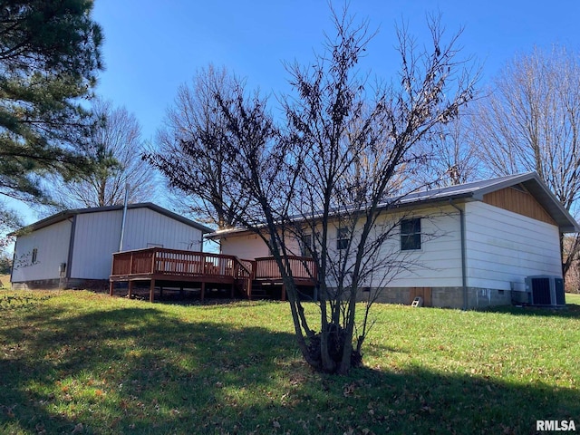 rear view of house featuring central AC unit, a wooden deck, and a yard