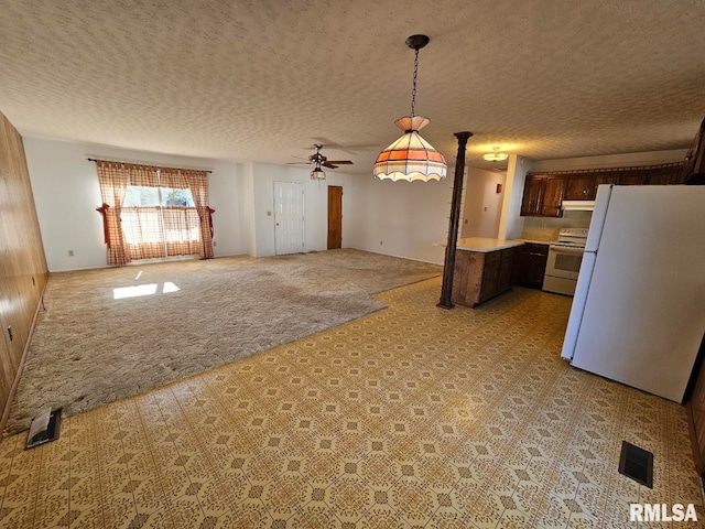 kitchen featuring light colored carpet, a textured ceiling, ceiling fan, white appliances, and decorative light fixtures