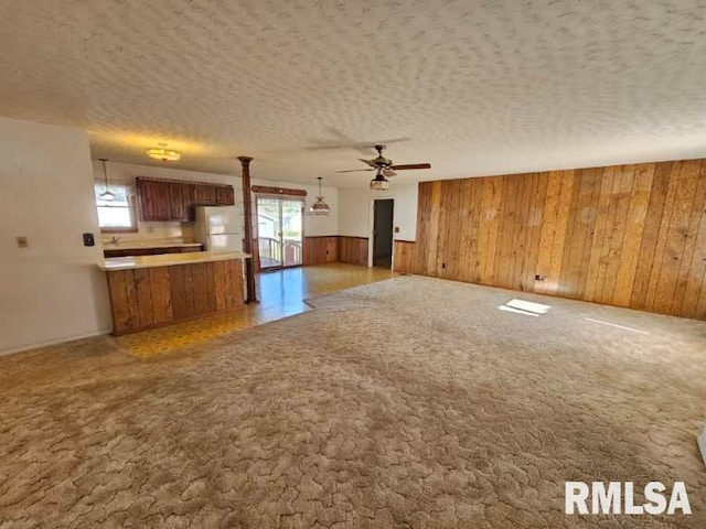 kitchen featuring wood walls, plenty of natural light, hanging light fixtures, and white refrigerator