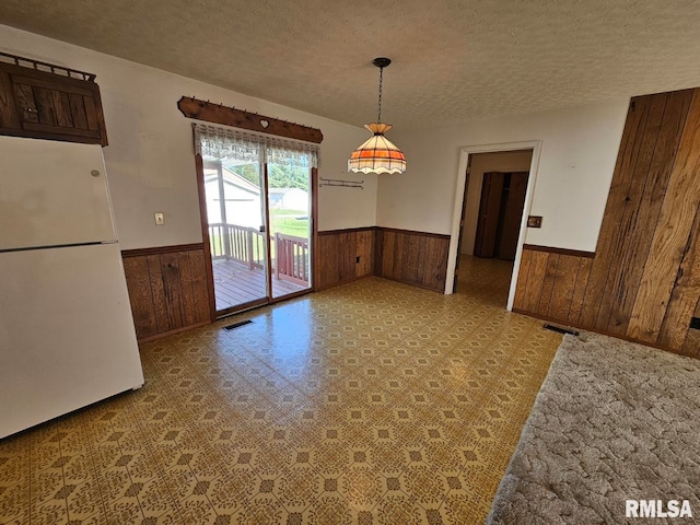 unfurnished dining area with wood walls and a textured ceiling