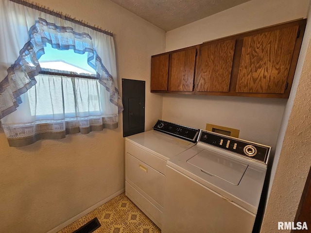 laundry area featuring electric panel, cabinets, washing machine and clothes dryer, and a textured ceiling