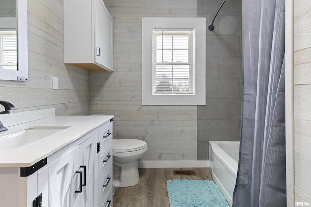 full bathroom with vanity, wooden walls, hardwood / wood-style flooring, toilet, and shower / bathtub combination with curtain