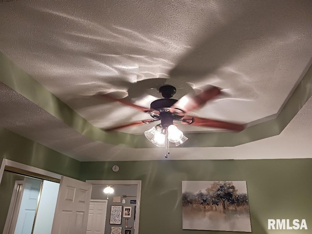 interior details featuring a tray ceiling, ceiling fan, and a textured ceiling