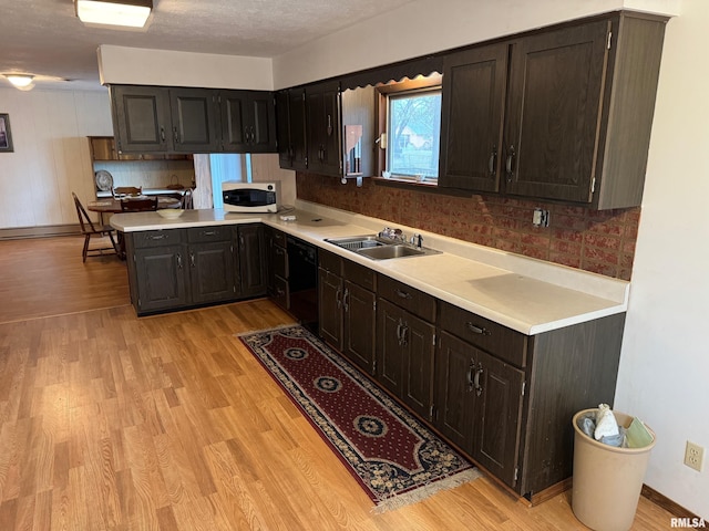 kitchen featuring dishwasher, sink, light hardwood / wood-style flooring, a textured ceiling, and kitchen peninsula