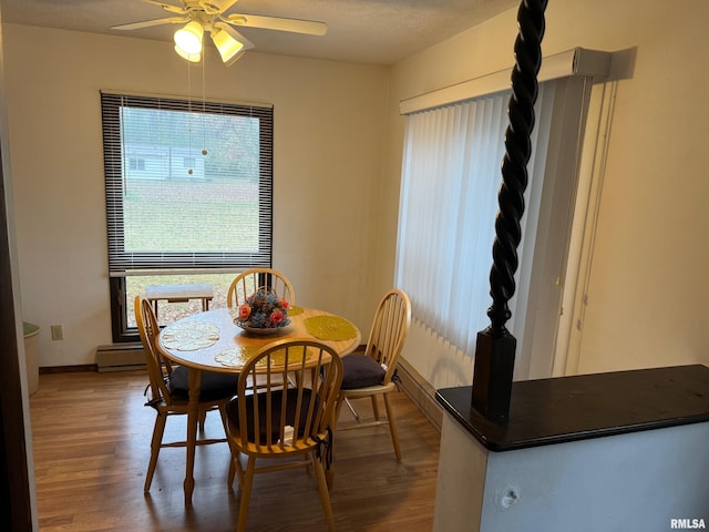 dining area featuring hardwood / wood-style flooring, ceiling fan, a textured ceiling, and a baseboard heating unit