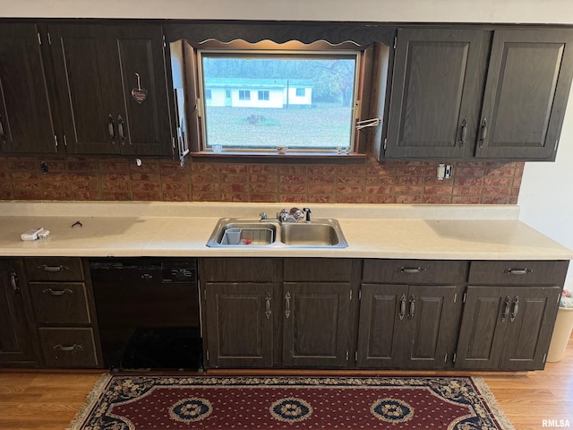 kitchen with black dishwasher, light hardwood / wood-style floors, backsplash, and sink