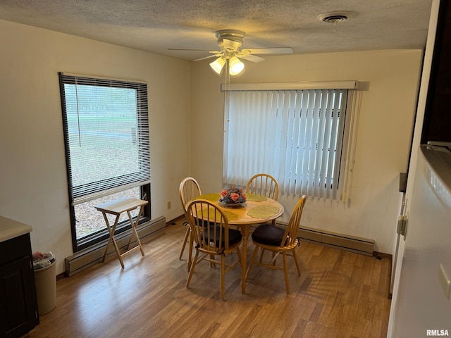 309 E Gelston St, Valier, IL 62891 - dining room with a baseboard heating unit, light wood-style flooring, a ceiling fan, and a textured ceiling