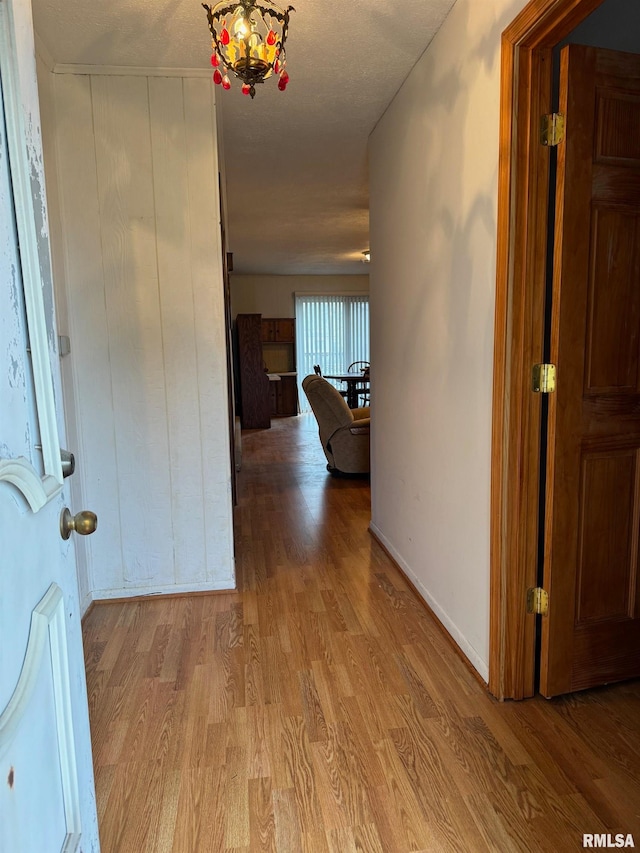 hall featuring a textured ceiling and light hardwood / wood-style floors