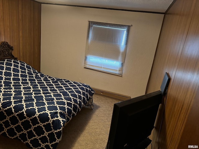 bedroom with carpet flooring, ornamental molding, a textured ceiling, a baseboard radiator, and wood walls