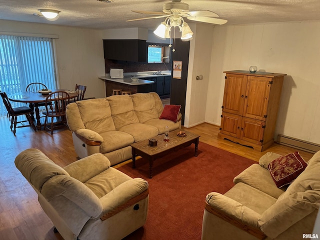 living room featuring ceiling fan, plenty of natural light, a baseboard radiator, and dark hardwood / wood-style floors