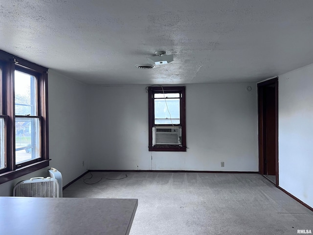 spare room with cooling unit, light carpet, and a textured ceiling