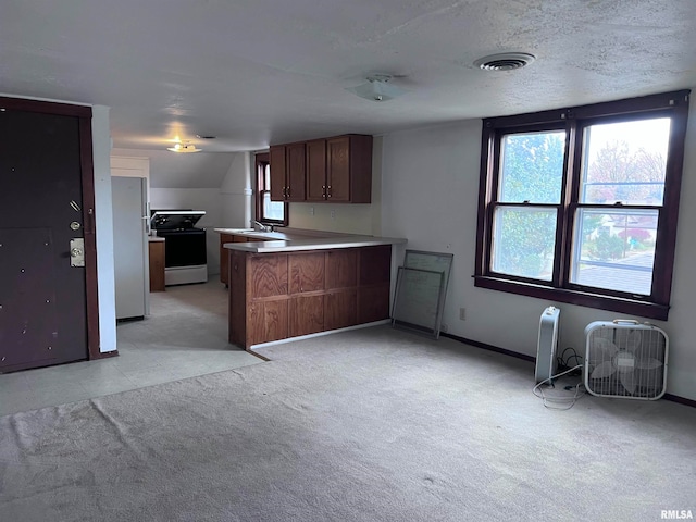 kitchen featuring sink, fridge, vaulted ceiling, stove, and kitchen peninsula