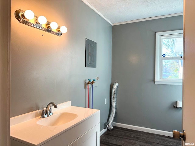 bathroom with electric panel, hardwood / wood-style floors, a textured ceiling, vanity, and ornamental molding