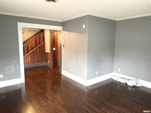 empty room featuring a textured ceiling, dark wood-type flooring, and ornamental molding