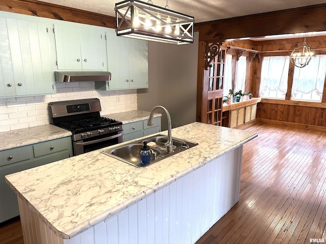 kitchen with gas stove, sink, hanging light fixtures, an island with sink, and a textured ceiling