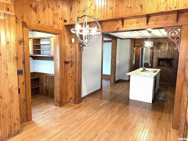 kitchen featuring stainless steel refrigerator, hanging light fixtures, light hardwood / wood-style flooring, a notable chandelier, and wood walls