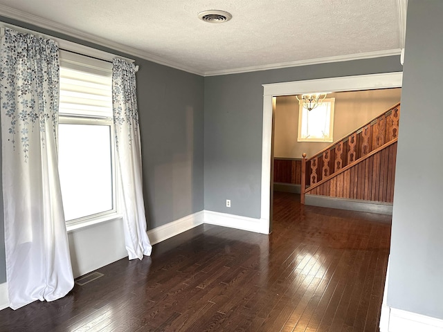 spare room with a chandelier, a textured ceiling, dark hardwood / wood-style floors, and crown molding