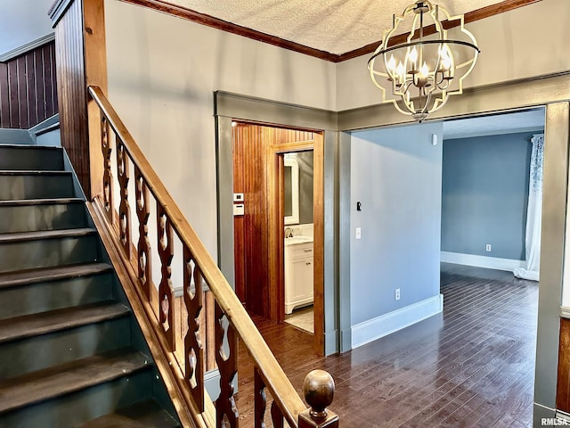 staircase with sink, crown molding, a textured ceiling, a notable chandelier, and wood-type flooring