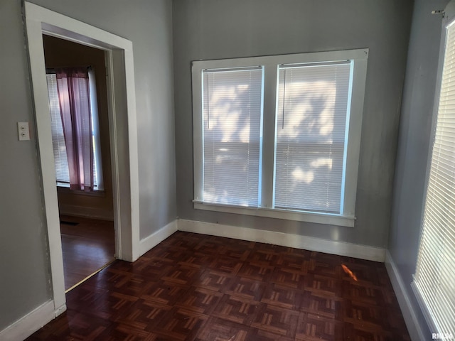 unfurnished room featuring dark parquet floors and a healthy amount of sunlight