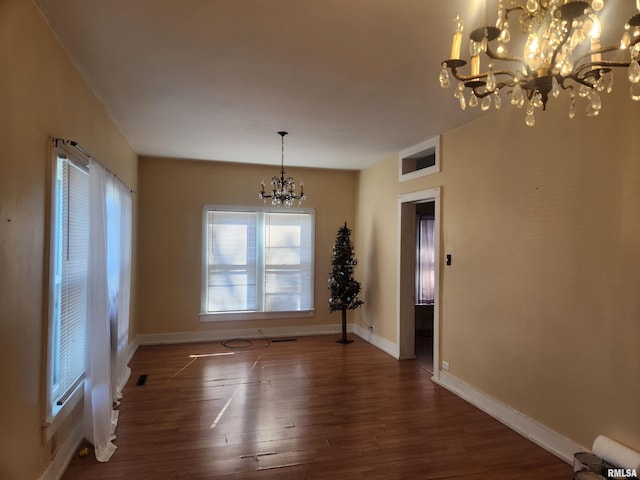 unfurnished dining area with dark hardwood / wood-style flooring and an inviting chandelier