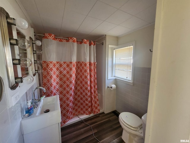 bathroom with sink, hardwood / wood-style flooring, toilet, tile walls, and curtained shower