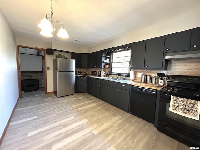 kitchen with wall chimney exhaust hood, sink, light hardwood / wood-style flooring, hanging light fixtures, and black appliances