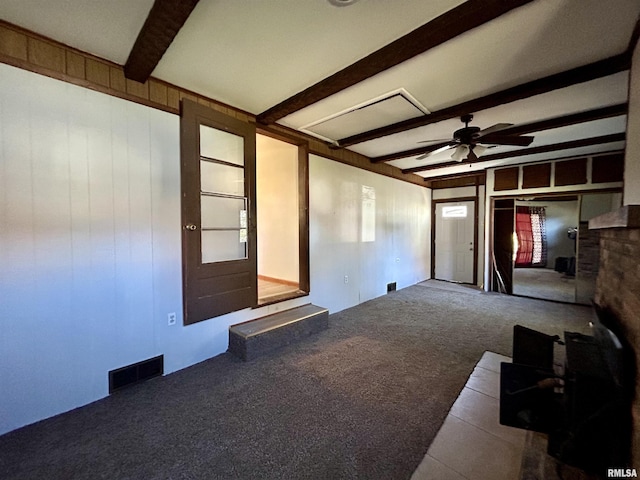 unfurnished living room featuring beam ceiling, ceiling fan, and carpet flooring