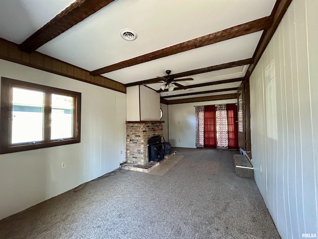 unfurnished living room with ceiling fan, carpet floors, and beam ceiling