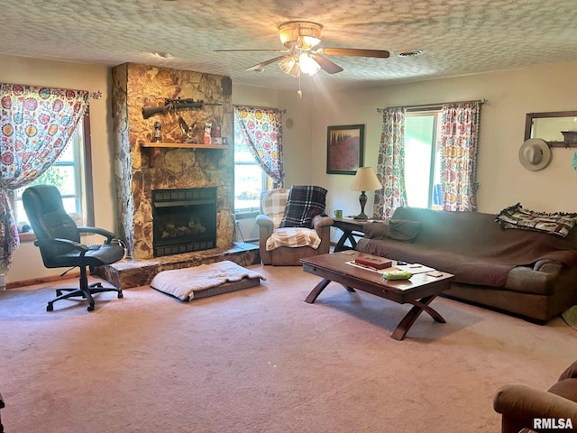 living room featuring carpet flooring, a textured ceiling, ceiling fan, and a fireplace