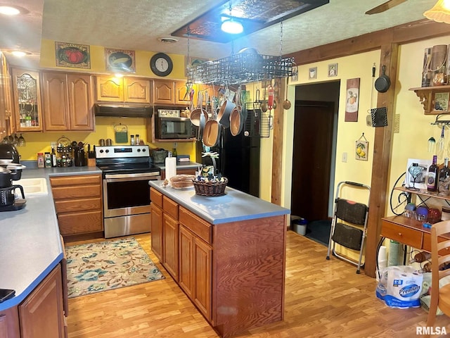 kitchen with hanging light fixtures, light hardwood / wood-style floors, a textured ceiling, appliances with stainless steel finishes, and a kitchen island