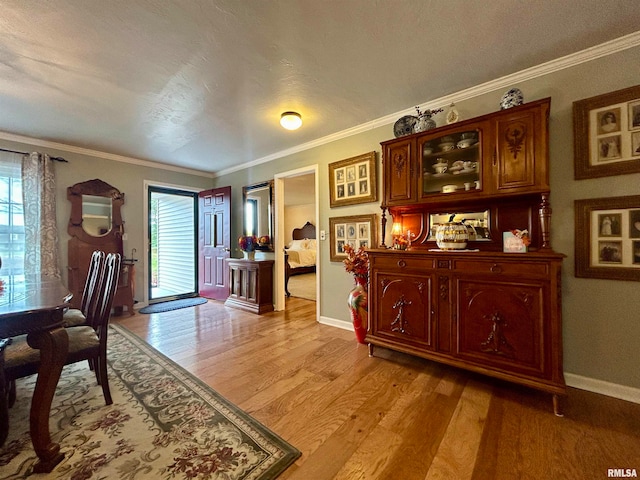 dining room featuring a textured ceiling, light wood-type flooring, plenty of natural light, and crown molding