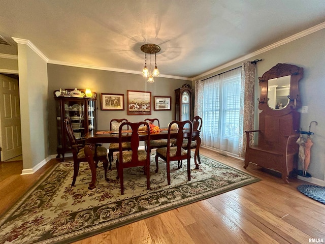 dining space with hardwood / wood-style flooring, a notable chandelier, and crown molding