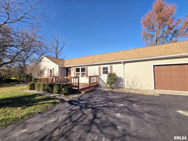 single story home featuring a wooden deck, a front lawn, and a garage