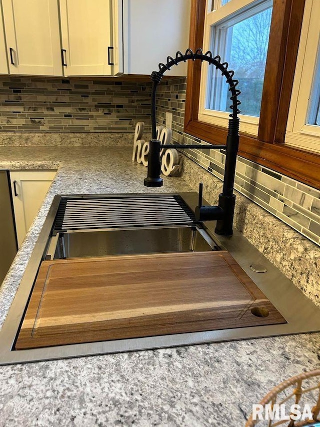 room details featuring white cabinetry, decorative backsplash, and sink