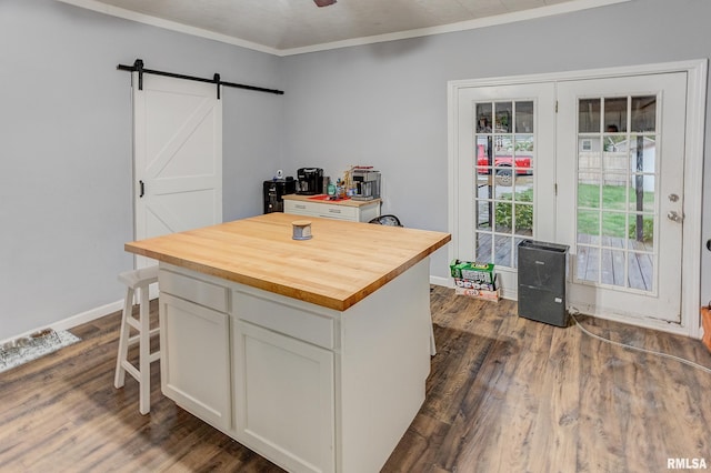 kitchen featuring dark hardwood / wood-style flooring, a barn door, white cabinets, a center island, and butcher block counters