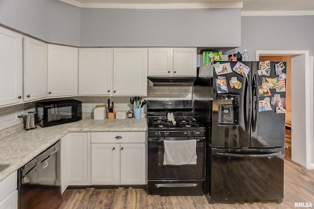 kitchen featuring black appliances, decorative backsplash, white cabinets, and hardwood / wood-style flooring