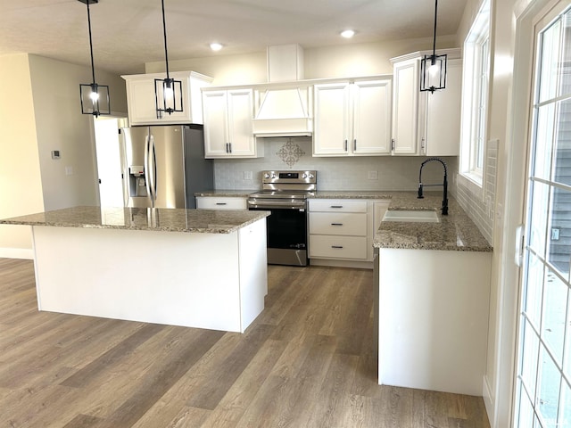 kitchen featuring stainless steel appliances, sink, hardwood / wood-style flooring, a center island, and hanging light fixtures