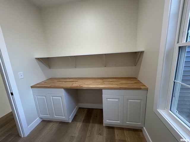 unfurnished office featuring dark hardwood / wood-style floors and built in desk