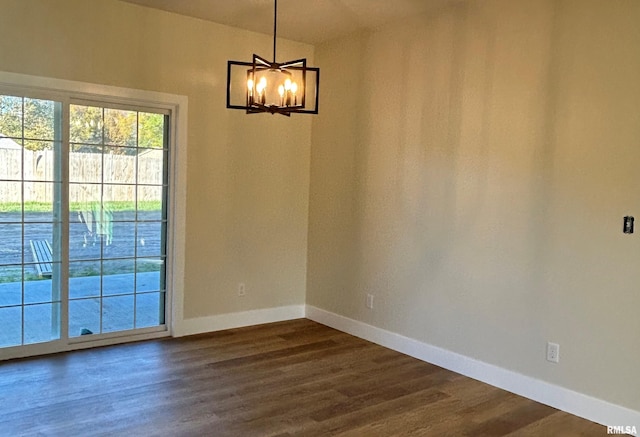 empty room featuring dark wood-type flooring and a chandelier