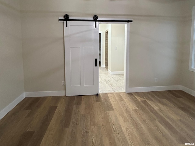 unfurnished room with a barn door and hardwood / wood-style floors