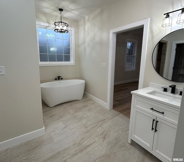 bathroom featuring vanity, a bath, and an inviting chandelier