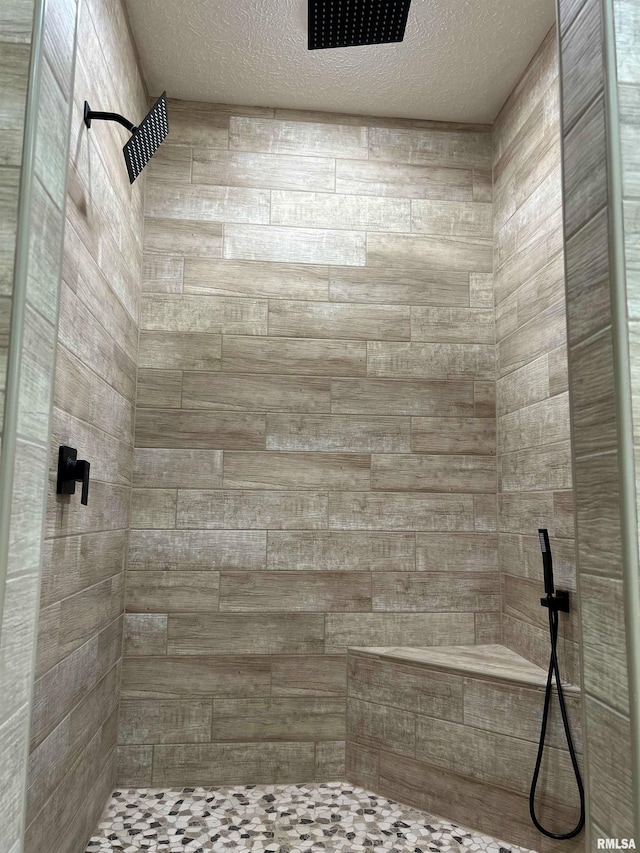 bathroom with tiled shower and a textured ceiling