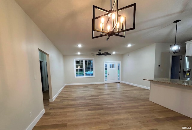 interior space featuring wood-type flooring, ceiling fan with notable chandelier, and vaulted ceiling